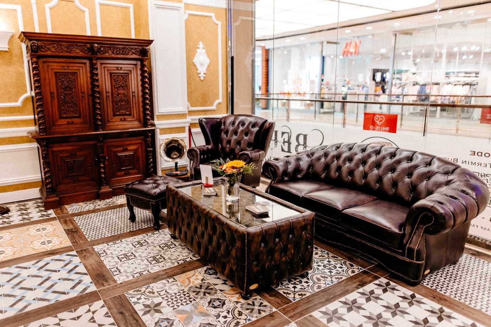 Warte-Lounge mit Chesterfield-Sofa und antikem Holzschrank